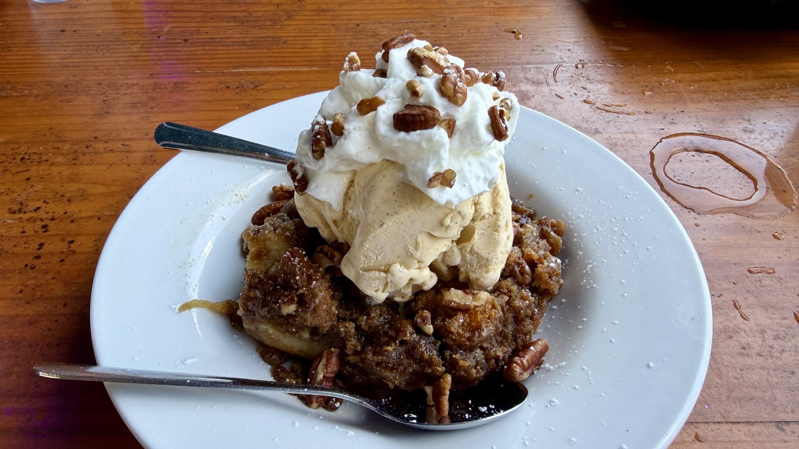 Warm apple cobbler with ice cream, whipped cream and pecans