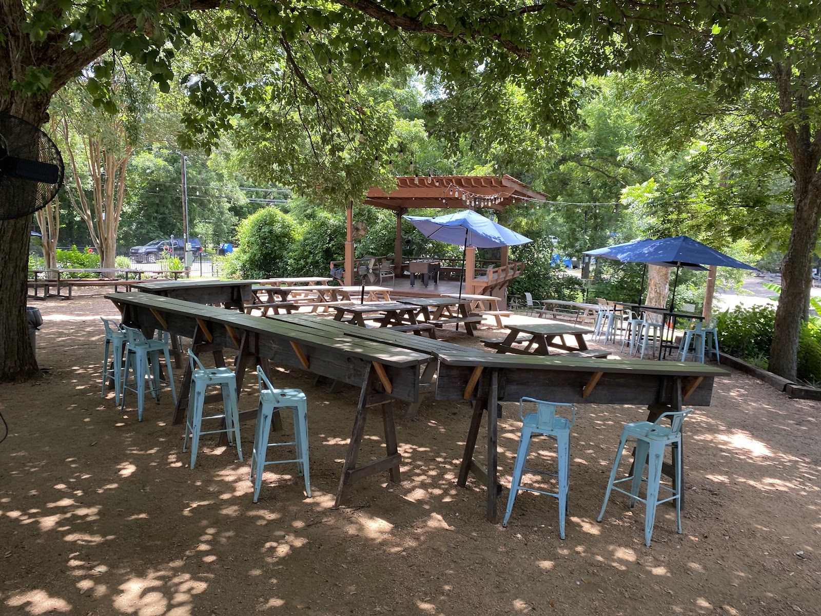 Shaded outdoor patio seating under trees at Ivar's River Pub
